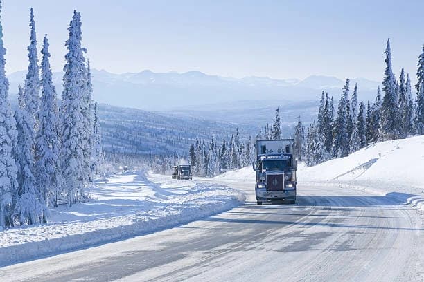 Freight truck driving through a snowy mountain road in Alaska